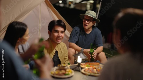Group of Happy Asian man and woman enjoy and fun outdoor lifestyle travel nature camping in forest on summer vacation. People friends having dinner eating bbq grill and drinking beer together at night photo