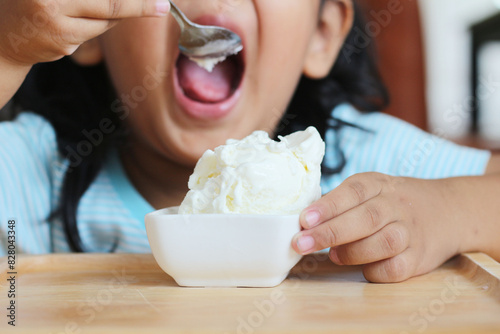 child is eating bowl of ice cream from spoon.