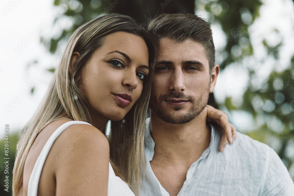 Fototapeta premium Smiling couple in white, sitting on bench