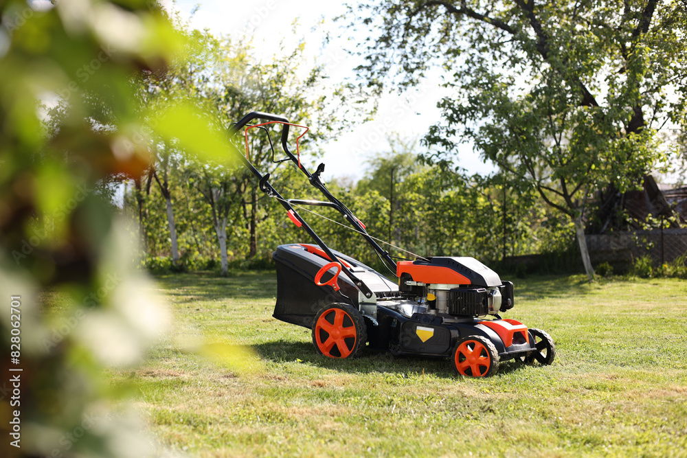 Modern lawn mower on green grass in garden Modern lawn mower on green grass in garden