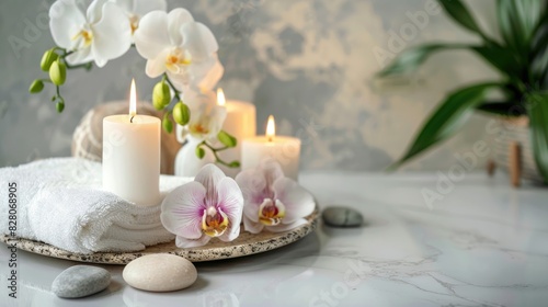 Spa arrangement featuring candles towel orchid and pumice stone on a light backdrop