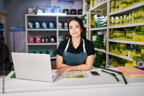 young latin american woman sitting at the counter of a small auto parts business photo