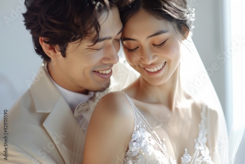 A beautiful couple's wedding dress, the woman standing and hugging the man from behind the woman's head resting on the man's shoulder, the woman's hand covering her face, portrait shot, head in focus,