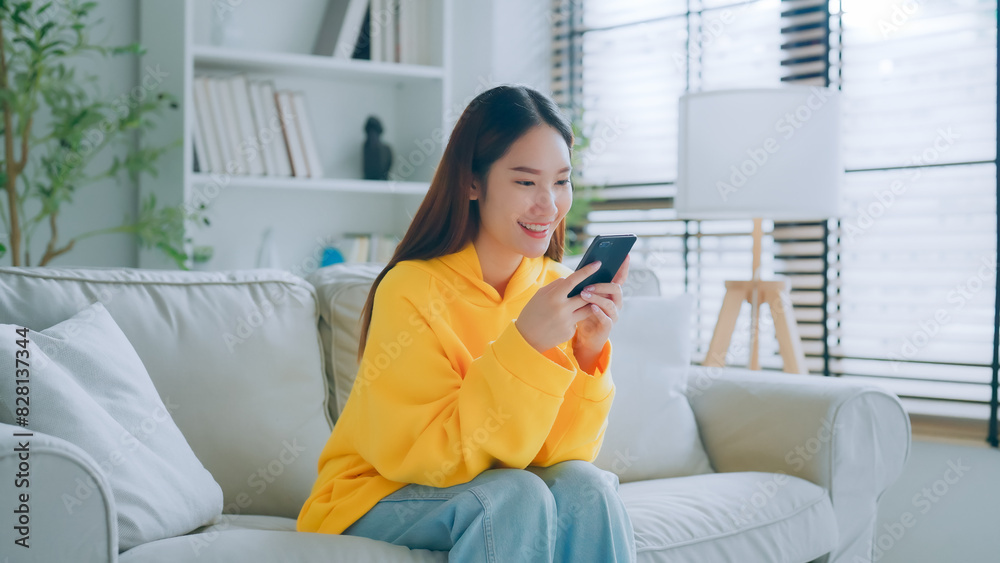 Happy young asian woman relax on comfortable couch at home texting messaging on smartphone, smiling girl use cellphone chatting, online shopping at home, video call communication Happy young asian woman relax on comfortable couch at home texting messaging on smartphone, smiling girl use cellphone chatting, online shopping at home, video call communication