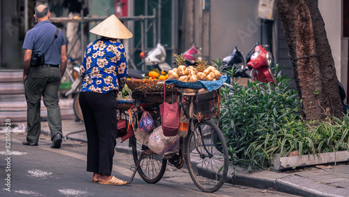 A Vietnamese street vendor woman selling tropical fruits from bicycle. Vietnam
