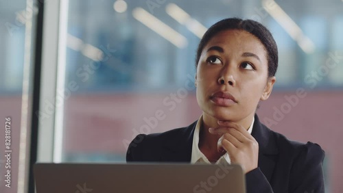 Concentrated business woman trader working looking at laptop computer screen thinking analyzing online trading market finance digital data. African american woman work in office and look at laptop