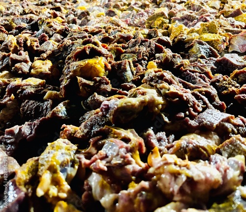 Close-up of raw beef pieces seasoned with vibrant turmeric powder, ready for cooking. The rich yellow spice contrasts beautifully with the fresh meat, highlighting a traditional culinary preparation p