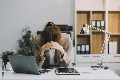 Asian women sitting in an office With stress and eye strain Tired, portrait of sad unhappy tired frustrated disappointed lady suffering from migraine sitting at the table, Sick worker concept photo