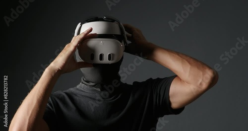 Man cheater in black mask puts on virtual reality headset.