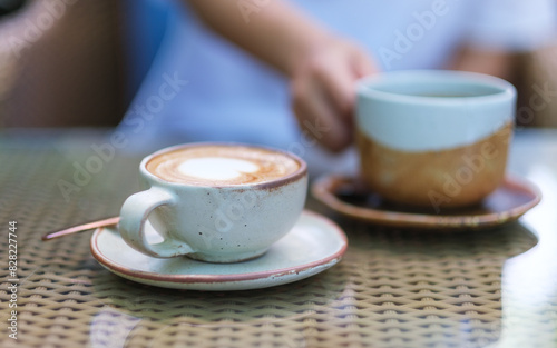 Closeup image of a woman holding and drinking coffee in the outdoors cafe