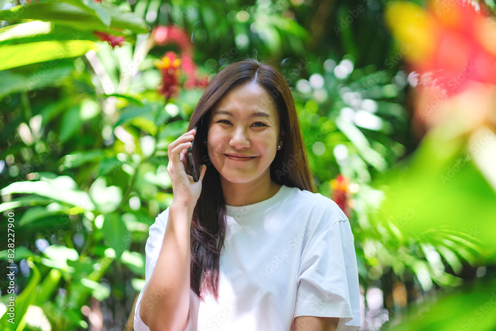 Portrait image of a young woman holding and talking on mobile phone in the garden Portrait image of a young woman holding and talking on mobile phone in the garden