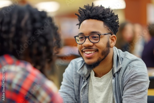 Smiling young man in glasses actively participating in a casual conversation in a group setting photo