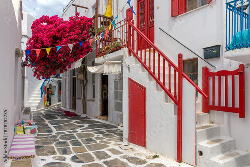 Traditional Cycladitic alley with a narrow street with a full blooming bougainvillea in Mykonos island, cyclades, Greece