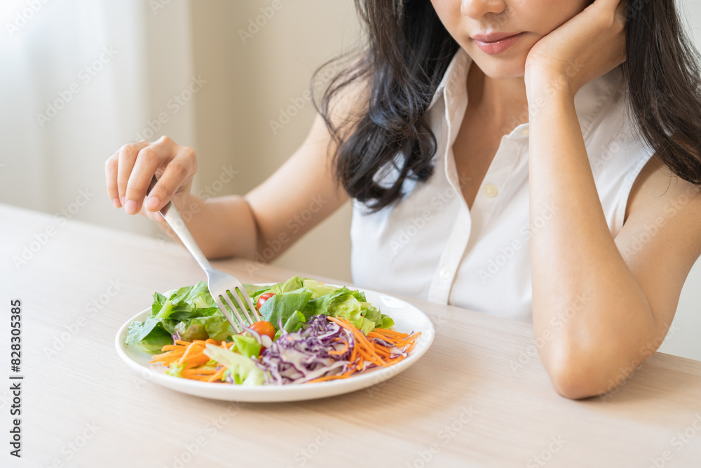Diet in bored face, unhappy beautiful asian young woman, girl on dieting, holding fork at tomato on salad plate, dislike or tired with eat fresh vegetables. Nutrition of clean, healthy food good taste Diet in bored face, unhappy beautiful asian young woman, girl on dieting, holding fork at tomato on salad plate, dislike or tired with eat fresh vegetables. Nutrition of clean, healthy food good taste
