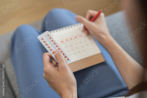 Contraception, menstruation and pregnancy concept, birth control pills asian young woman holding hormonal oral contraceptive pills with calendar, menstrual cycle. Prevention, safe virus sex disease.