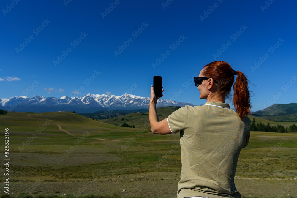 mature woman traveling stopped by the side of the road and takes pictures of the mountains on her phone mature woman traveling stopped by the side of the road and takes pictures of the mountains on her phone