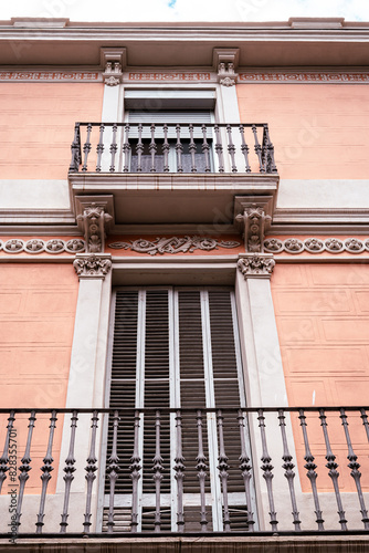 This image shows a classic European architectural style with two wrought-iron balconies on a peach-colored building, conveying a sense of urban living