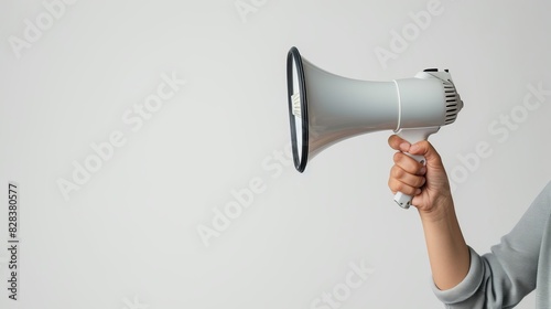 A hand holding a white megaphone on a white background. Copy space.