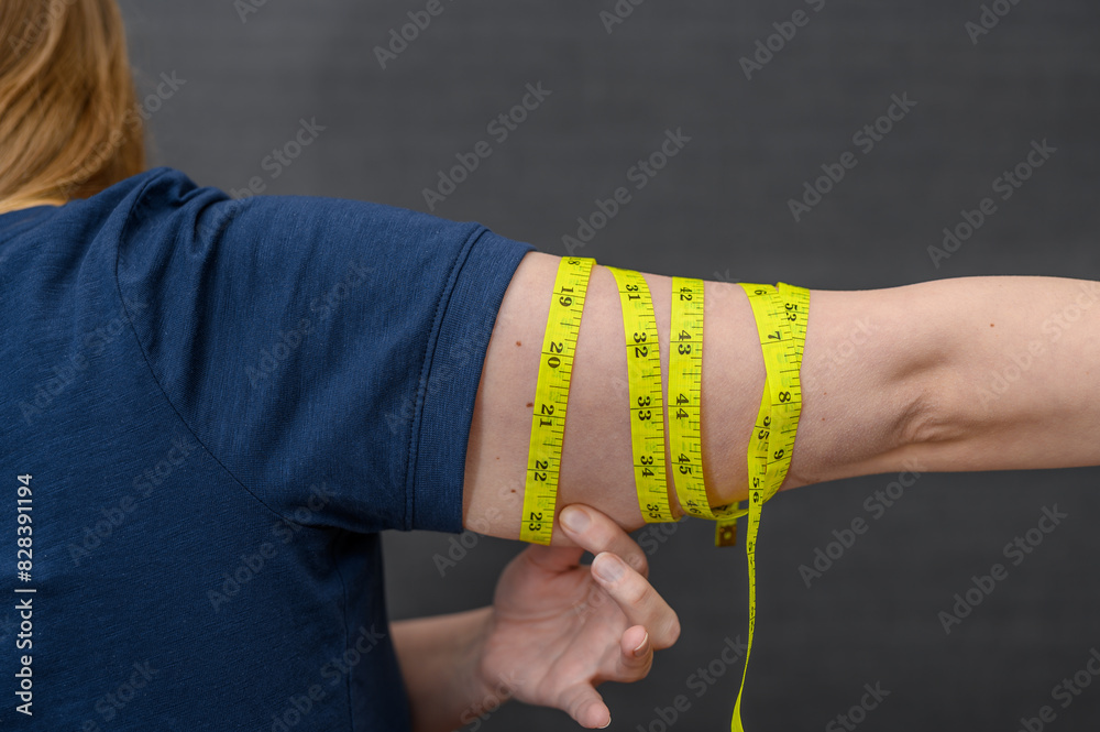 Obraz premium Obwisłe ramiona, kobieta mierzy obwód reki
