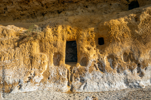 Cave windows of the Cala Blanca beach of the Puntas de Calnegre regional park in the Region of Murcia, Spain on the yellow rock walls photo