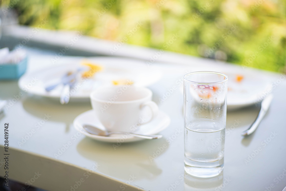 Table with glass of water, coffee cup, and plates with leftover food Table with glass of water, coffee cup, and plates with leftover food