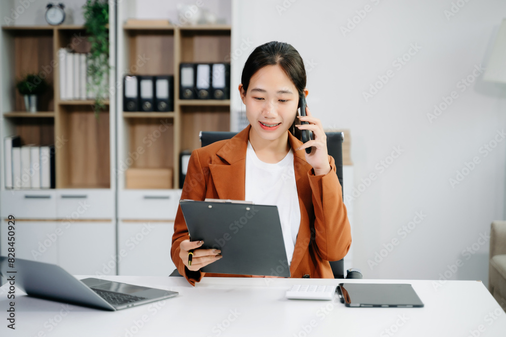 Asian woman using laptop and tablet while sitting at her working place. Asian woman using laptop and tablet while sitting at her working place.