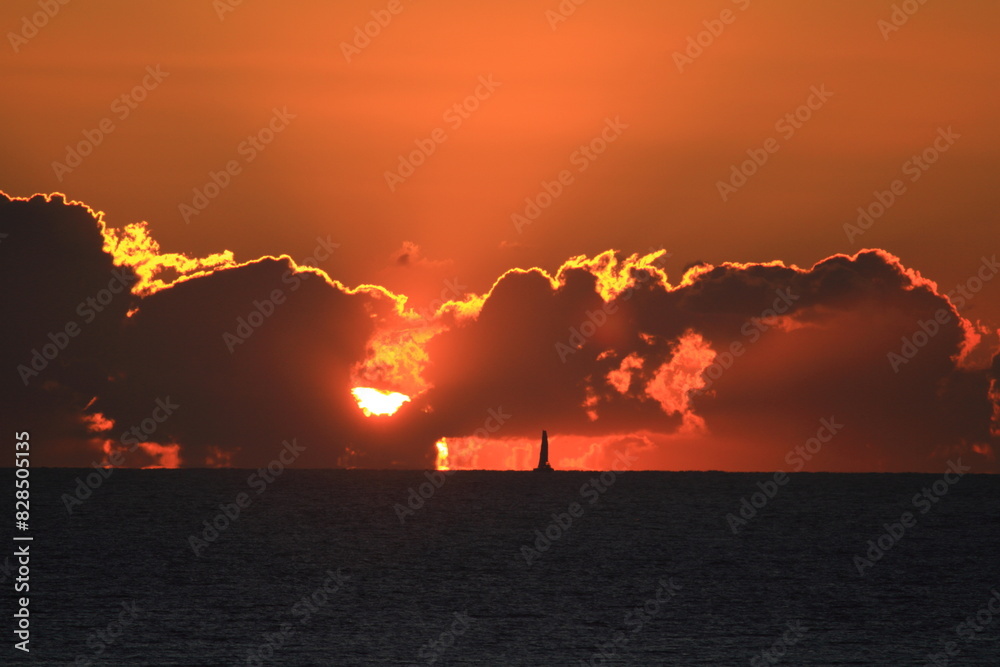 Obraz premium Sailboat silhouetted in the distance at dramatic sunset over the sea