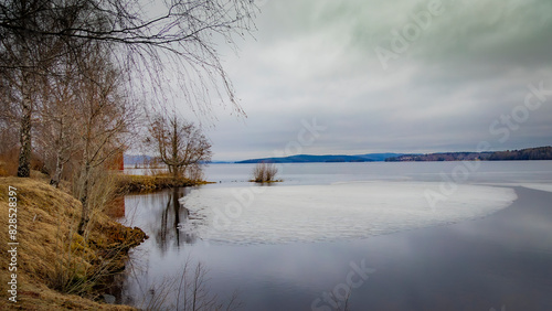 Vast lake bordered by lush greenery and trees under cloudy skies in Ludvika town, Sweden photo