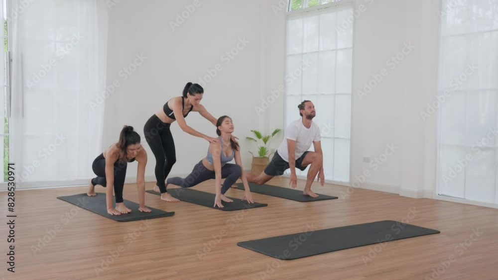 Group Yoga Class in a Bright Studio with Instructor Assisting Participants Group Yoga Class in a Bright Studio with Instructor Assisting Participants