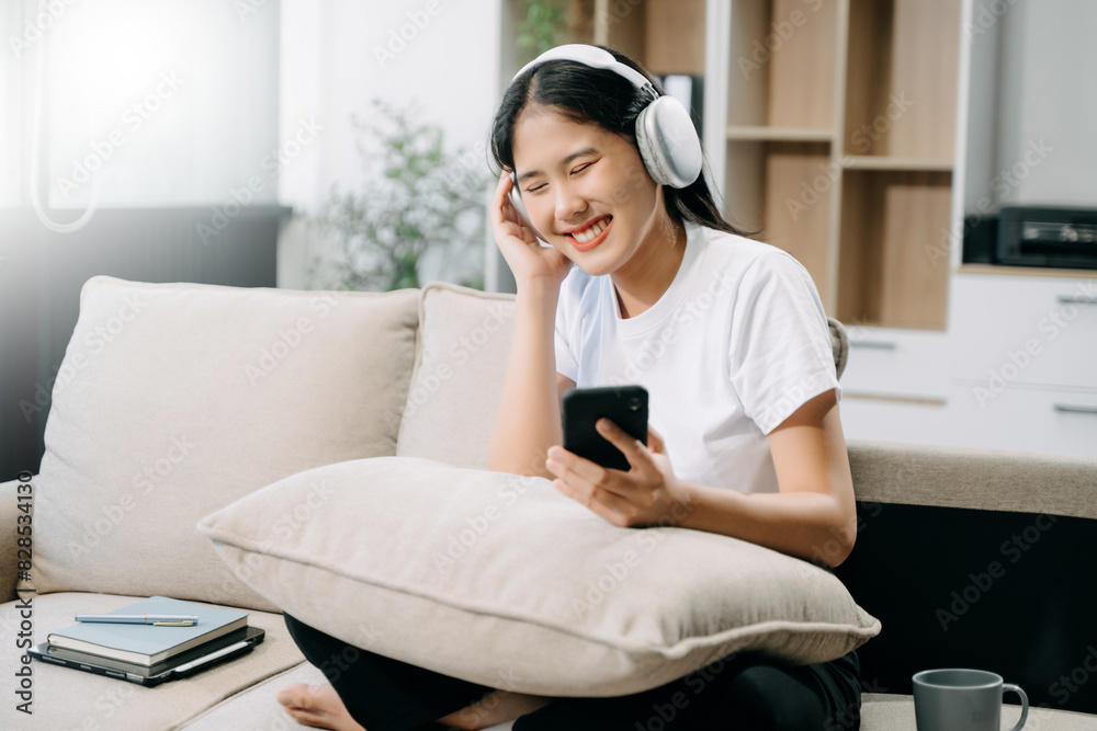 Young asian woman using smartphone and tablet while seated on couch Young asian woman using smartphone and tablet while seated on couch