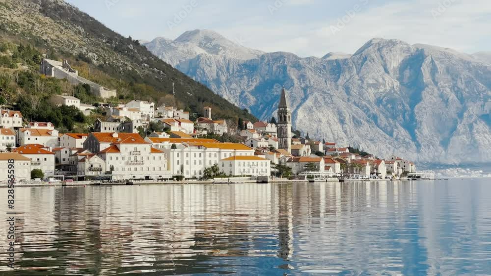 The Perast coast from the sea with the church of saint Nicholas in front of magnificent mountains The Perast coast from the sea with the church of saint Nicholas in front of magnificent mountains