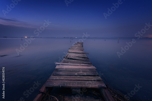 Old wooden walkway used as a pier in the Ebro Delta, Tarragona, just before the sun rises over the Mediterranean Sea photo
