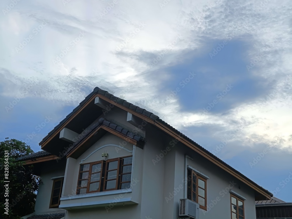 Modern Suburban House with Elegant Architectural Design Against a Backdrop of a Clear Blue Sky with Wispy Clouds Modern Suburban House with Elegant Architectural Design Against a Backdrop of a Clear Blue Sky with Wispy Clouds