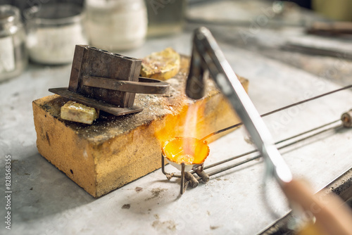 Heating with a flame jet of a metal billet of a silver ring. The work of a jeweler in the workshop photo