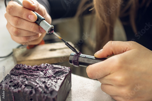 A female jeweler constructs a unique ring design using wax melting. Craft in a jewelry workshop photo