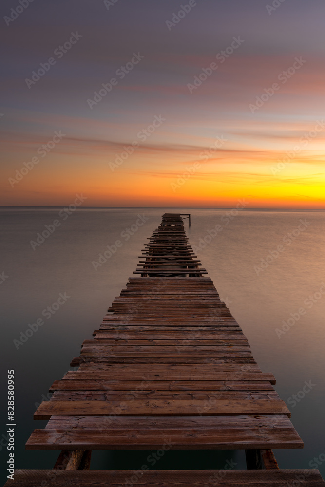 sunrise seascape with an old wooden dock leading out into the calm ocean waters sunrise seascape with an old wooden dock leading out into the calm ocean waters