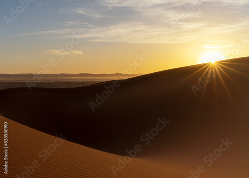 view of the sand dunes at Erg Chebbi in Morocco at sunset with a sunstar