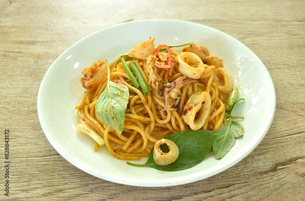 spicy stir fried spaghetti slice squid with chili and basil leaf in sauce on plate spicy stir fried spaghetti slice squid with chili and basil leaf in sauce on plate