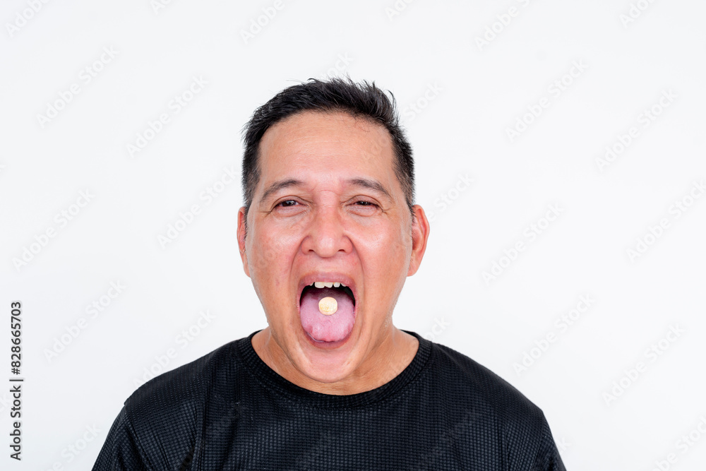 A man opens his mouth showing off a tablet inside his tongue, for medication purposes. Isolated on a white background. A man opens his mouth showing off a tablet inside his tongue, for medication purposes. Isolated on a white background.