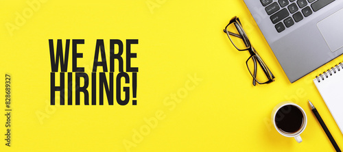 We are hiring. Desk with laptop, eye glasses, flower, pen and a cup of coffee. Still life, business, office supplies or education concept.