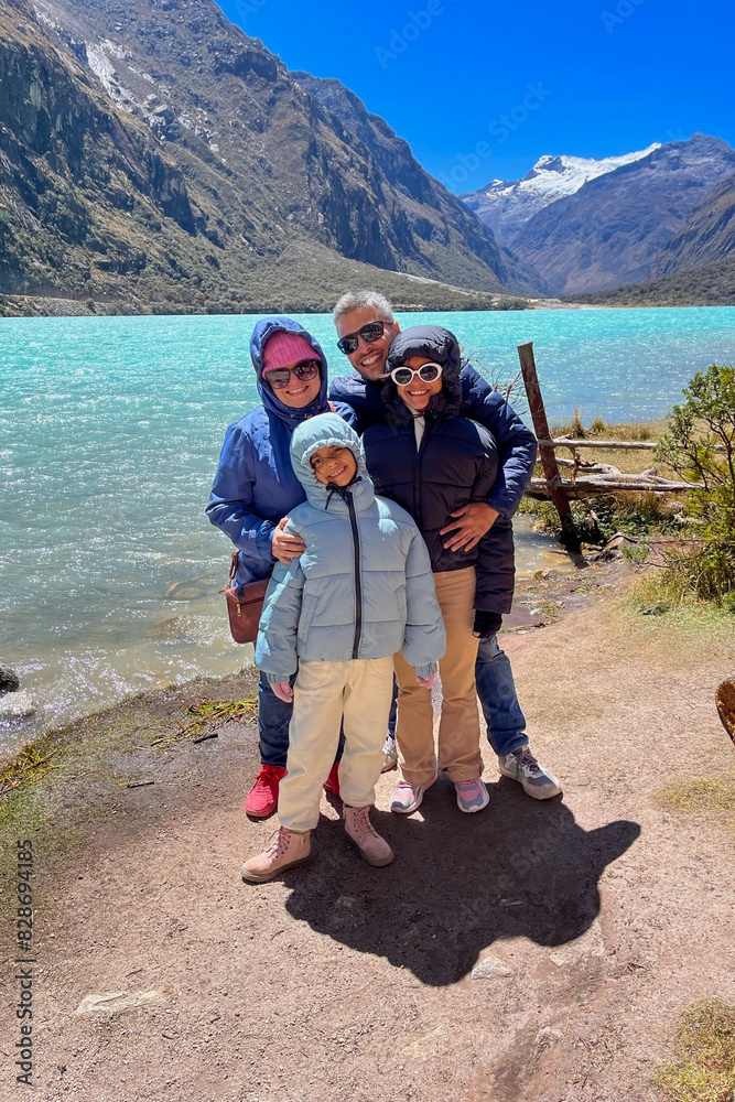 A family of four posing for a photo by a Llanganuco lagoon, Peru