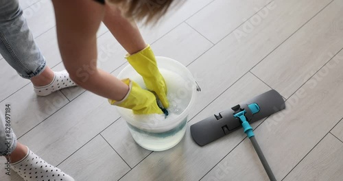 Housewife in rubber gloves wringed out blue rag. Professional cleaning and mopping photo