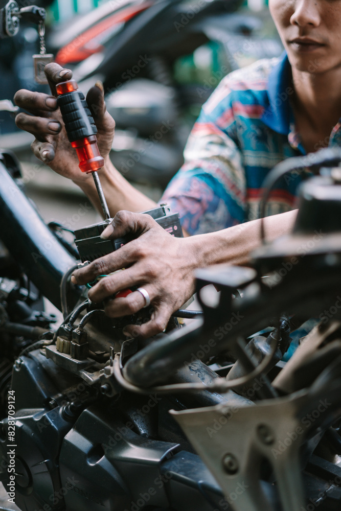 A motorcycle mechanic inspecting a damaged engine A motorcycle mechanic inspecting a damaged engine