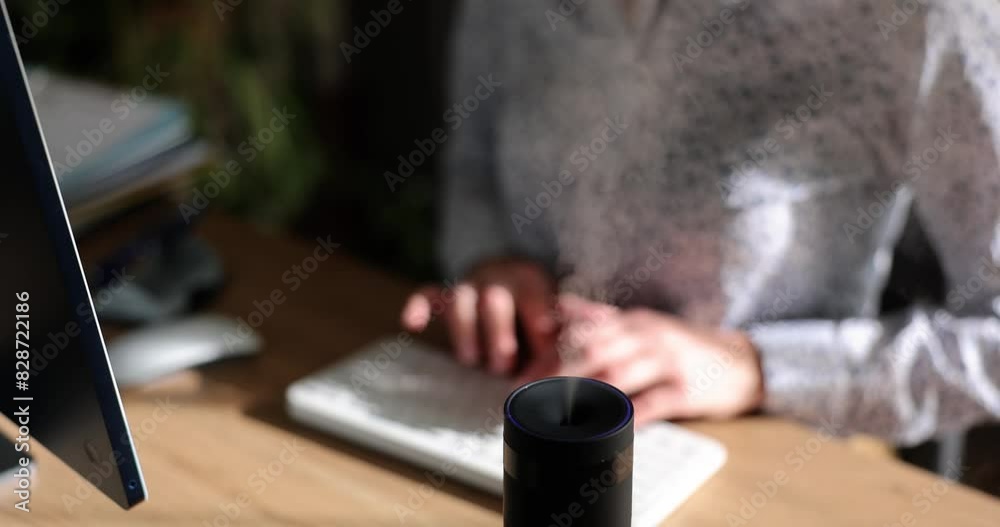 Modern air humidifier device during working hours. Manager using computer work on the Internet, enjoying aroma of aromatherapy steam from diffuser Modern air humidifier device during working hours. Manager using computer work on the Internet, enjoying aroma of aromatherapy steam from diffuser