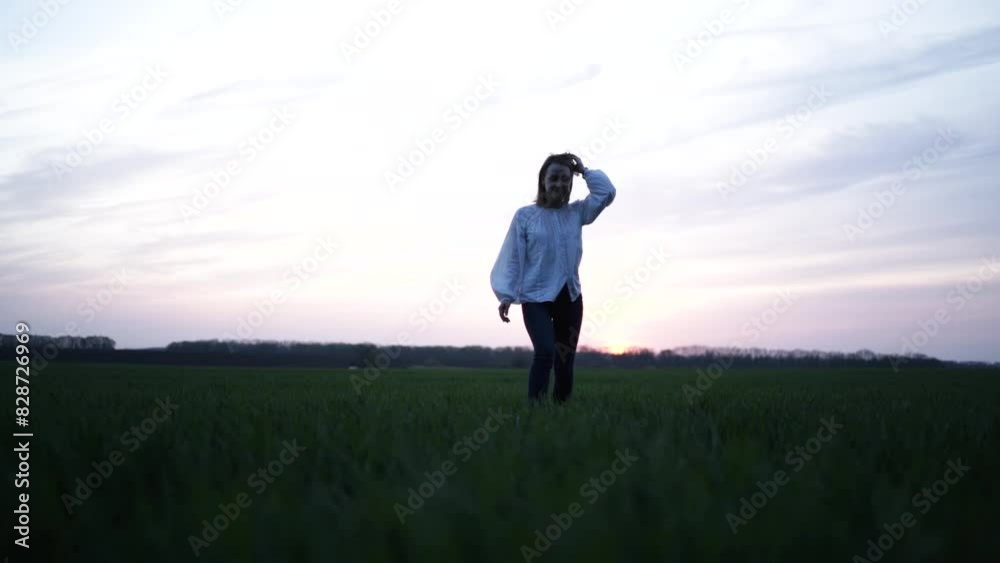 Beautiful girl walking on the green field. Girl at sunset on the wheat field Beautiful girl walking on the green field. Girl at sunset on the wheat field