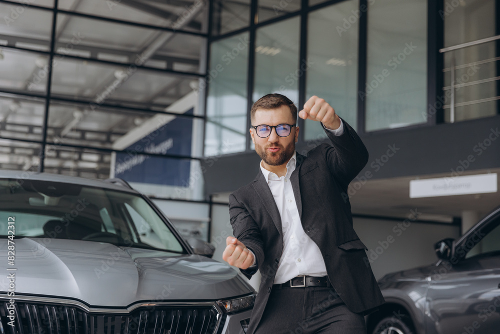 Yes, that's my new car! Customer in car dealership. Happy bearded man new car owner shows driving a car Yes, that's my new car! Customer in car dealership. Happy bearded man new car owner shows driving a car