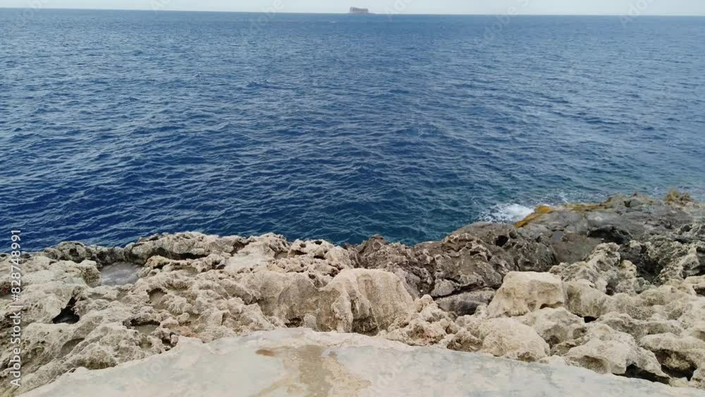 Blue mediterranean sea and rocky coast of Maltese island with Filfla uninhabited island in the distance. High quality 4k footage Blue mediterranean sea and rocky coast of Maltese island with Filfla uninhabited island in the distance. High quality 4k footage