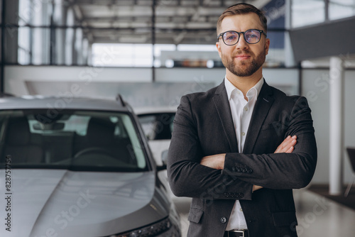 Portrait of Modern car seller standing in car salon with arms crossed with copy space