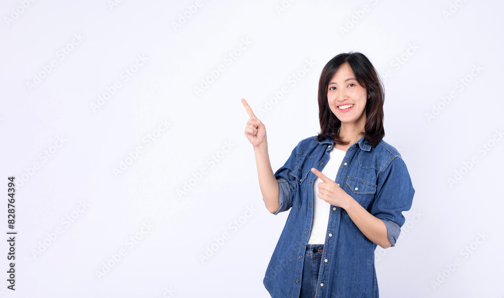 A young asian woman wearing denim jean while pointing finger to free copy space isolated on white studio background A young asian woman wearing denim jean while pointing finger to free copy space isolated on white studio background