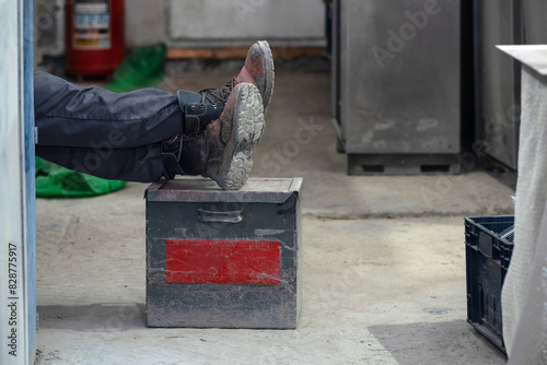 worker rests in the workshop with his feet on a box